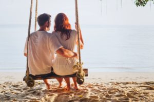 Young couple enjoying a beach swing